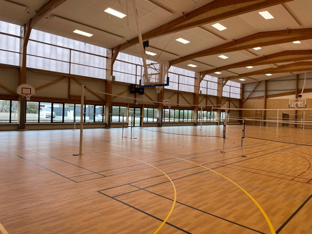 Cette image est une photographie d'une installation de badminton dans une salle de sport. Elle illustre l'ensemble des équipements sportifs de badminton que Nathis peut fournir et installer aux collectivités de Bretagne.