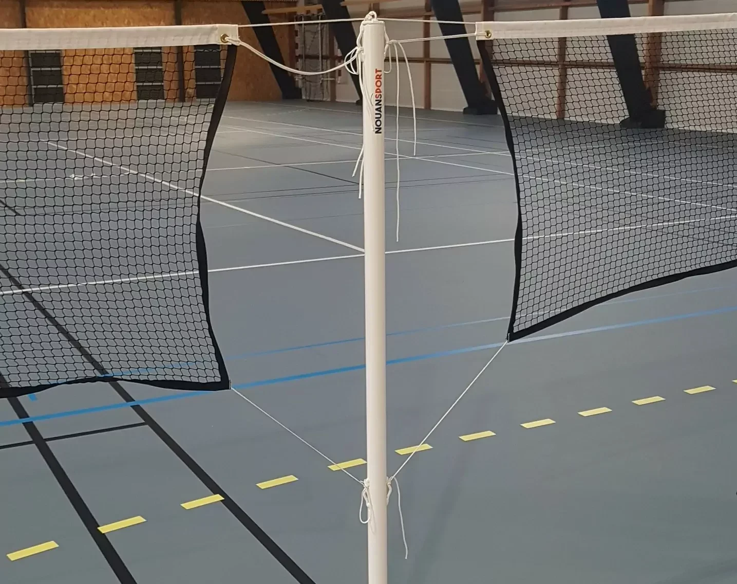 Cette image est une photographie d'un poteau de volley et de filets de volley. Elle illustre les équipements sportifs de volley que Nathis peut fournir et installer aux collectivités de Bretagne.