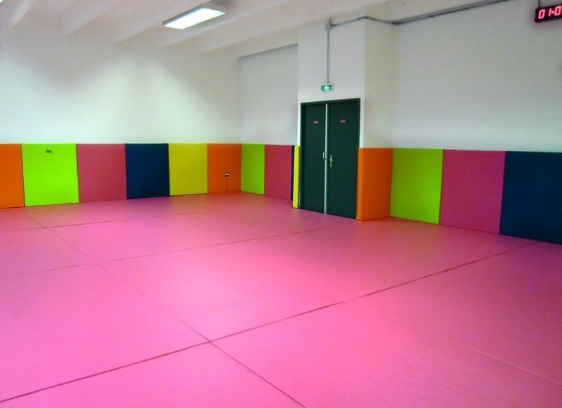 Cette image est une photographie d'une salle de sport équipée de protections de sols et de murs. Elle illustre l'ensemble des équipements sportifs de protection et d'éveil pour les enfants que Nathis peut fournir et installer en Bretagne.